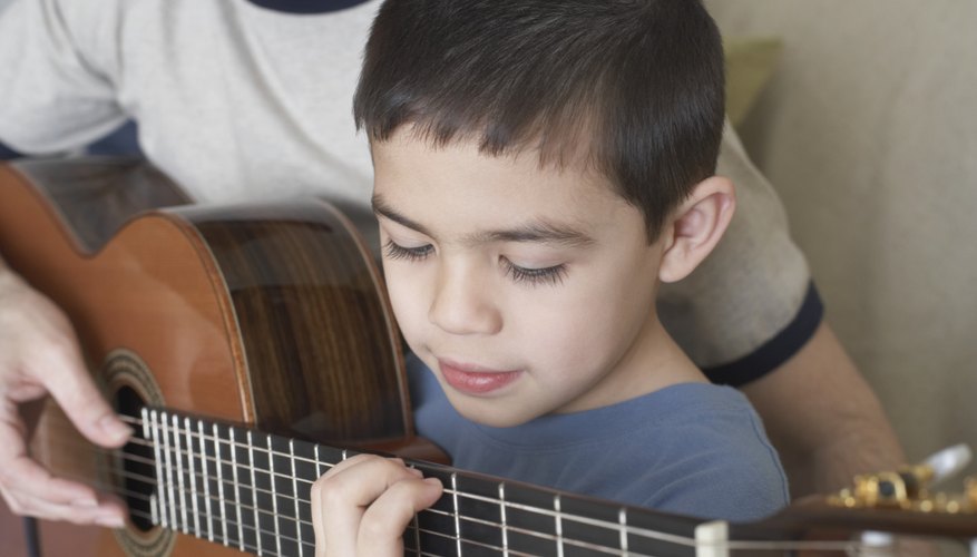 Young boy learning to play the guitar.