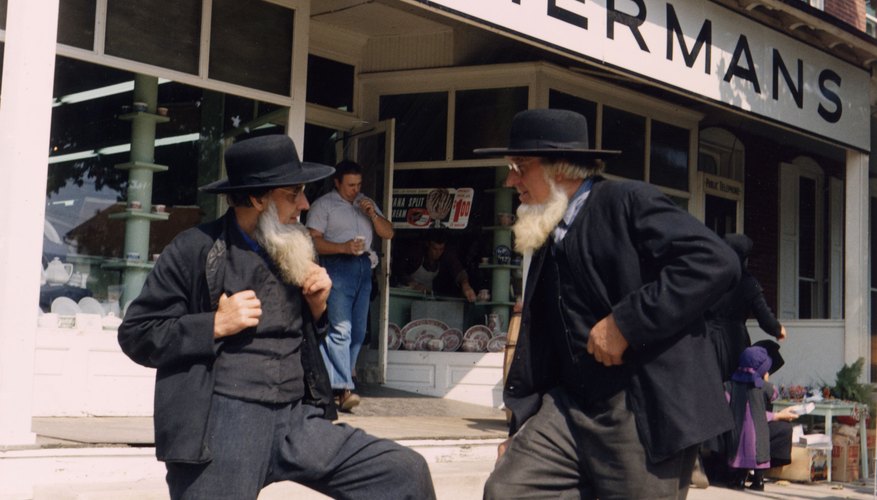 Two Amish men stand in front of a store in town.
