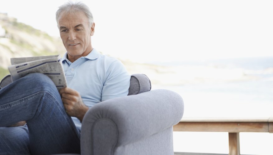 Man reading newspaper in chair.