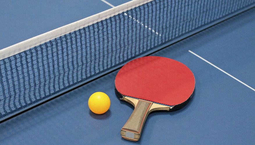 Paddle, ball and net on a ping pong table.