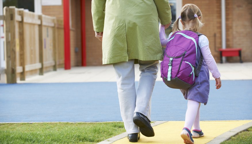 A young girl walks with her parent to school.
