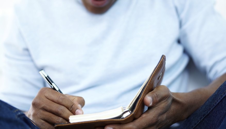 A close-up of a man writing in a notebook.