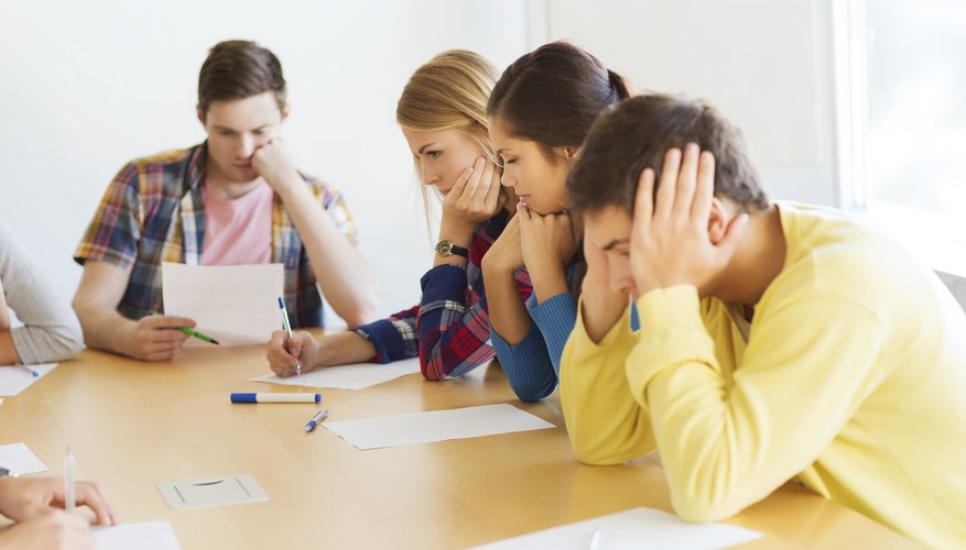 A group of teenagers at a table writing expressive letters.