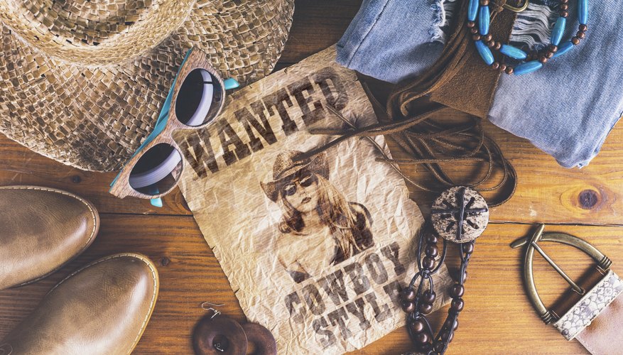 Cowboy accessories surrounding a wanted poster.