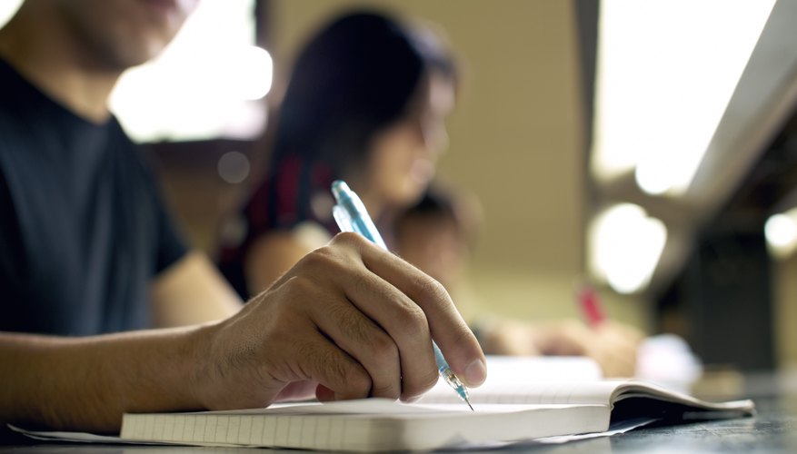 A student writing in a notebook in a library.