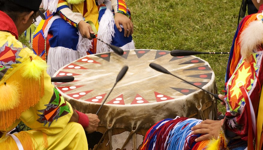 Several tribesmen beat a ceremonial drum