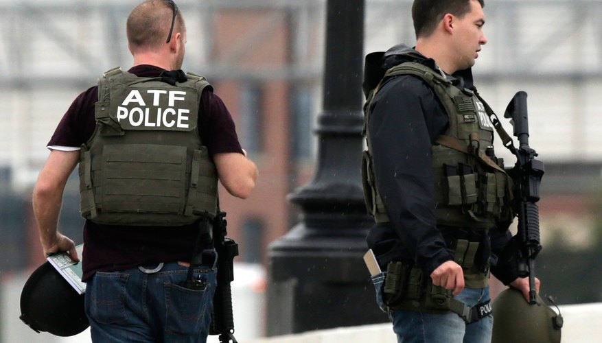 ATF agents carrying guns and wearing bulletproof vests.