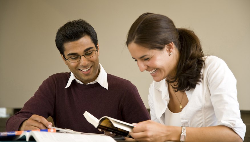 Students reading book at table.
