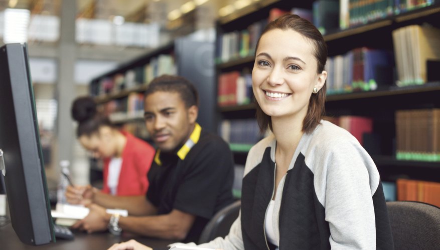 Three students perform school work in the library.
