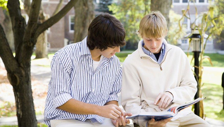 Two students reading through text book.