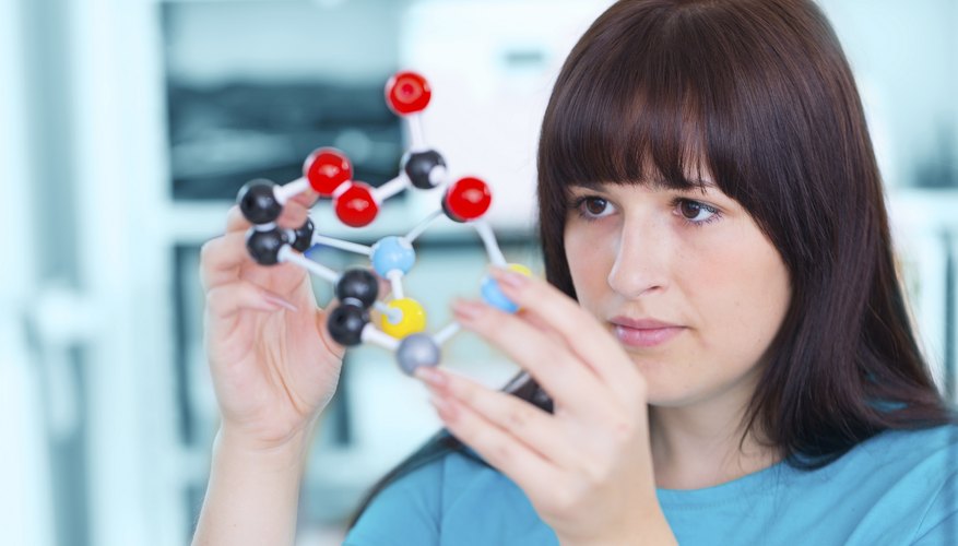 A teenage girl building a molecule model in a classroom.