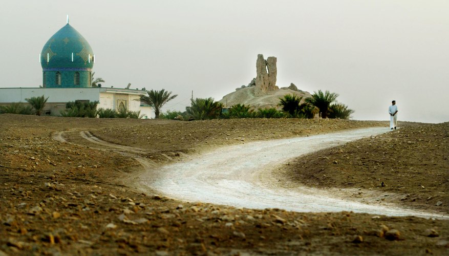 A road winds through a Mesopotamian landscape by an ancient shrine.