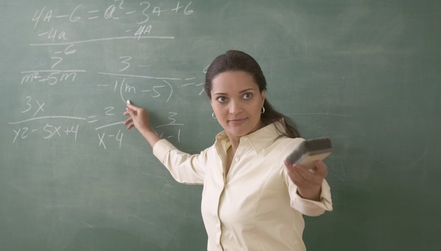 Teacher at blackboard solving a math problem.