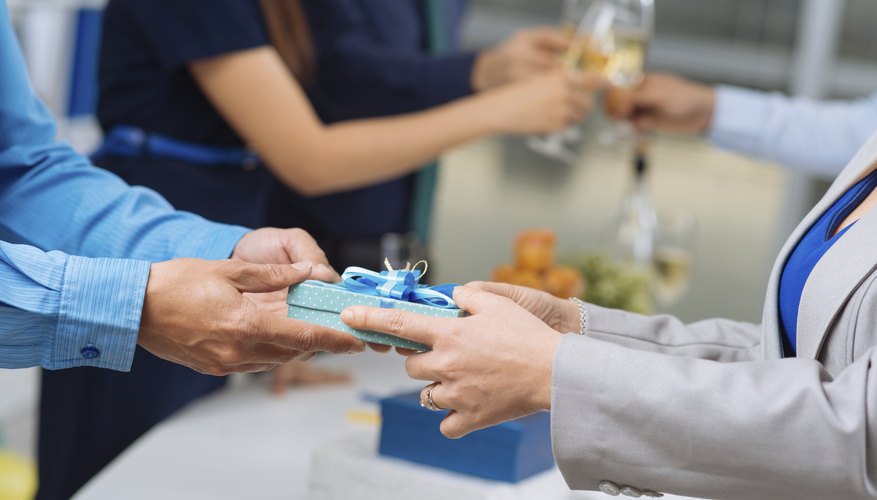 Businessman passing a colleague a small wrapped gift.