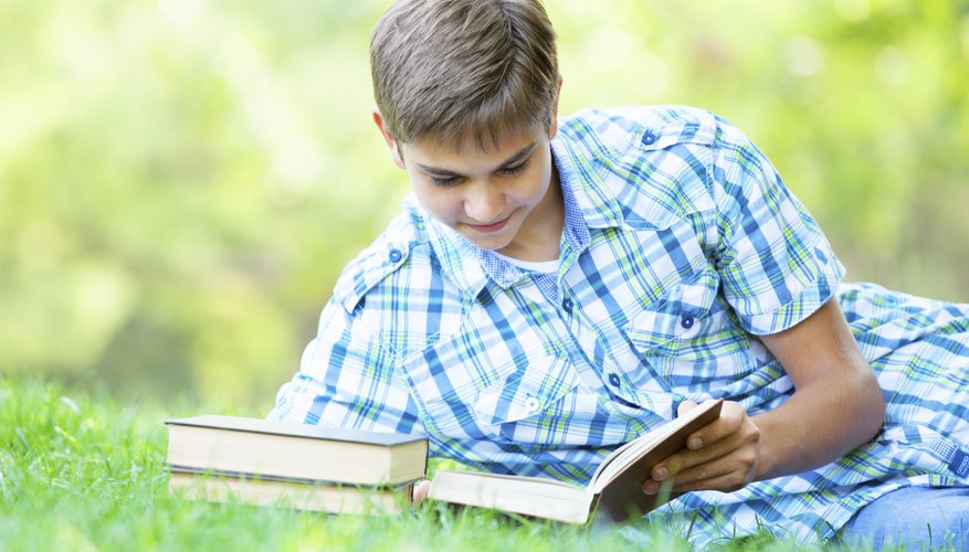 Teenager reading book on grass