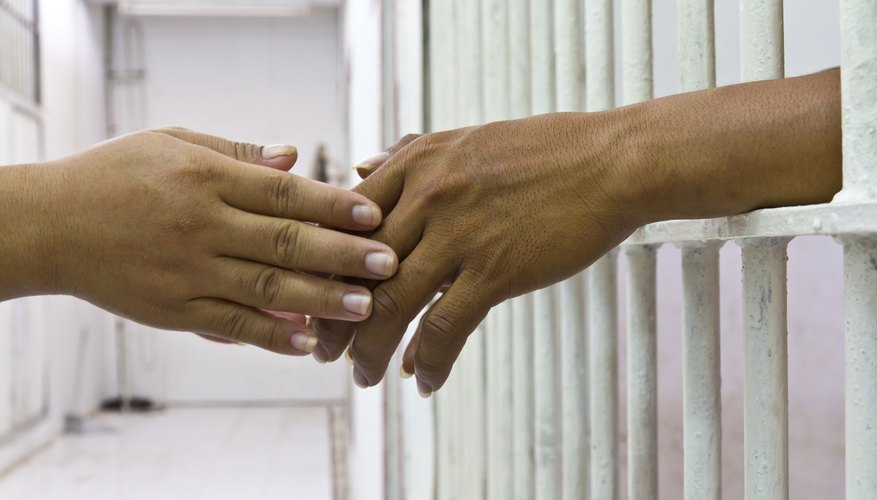 Close-up of two hands touching through prison bars