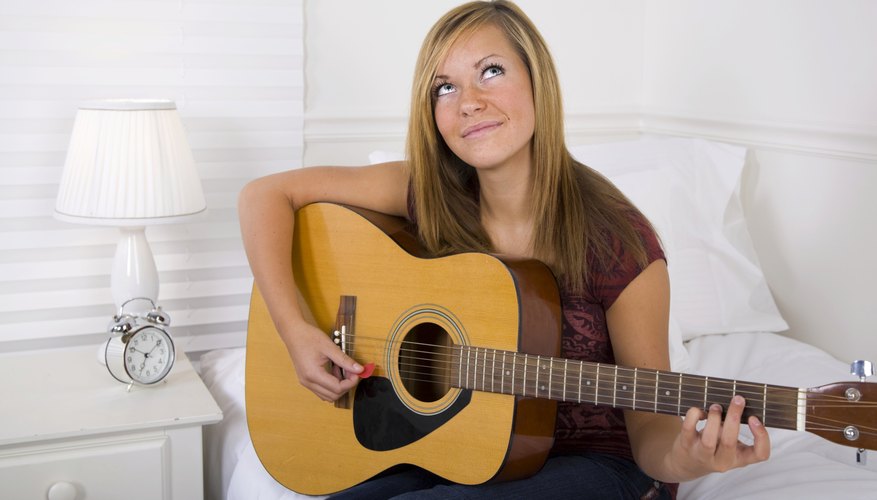 Girl playing guitar in dorm room.