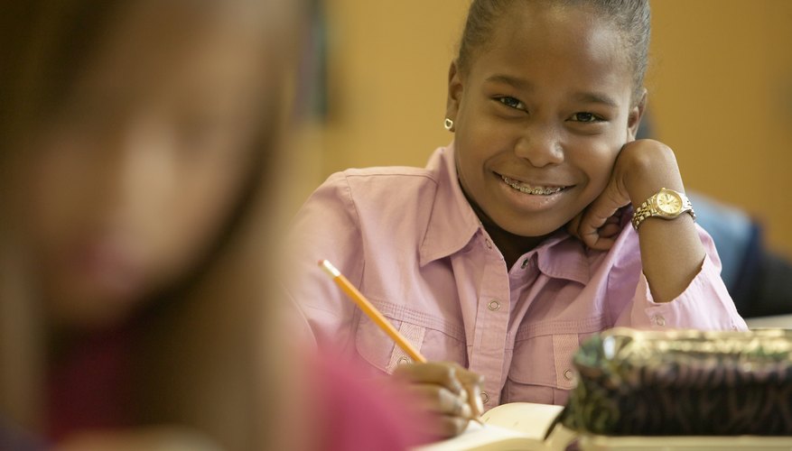 Elementary student taking notes at desk.