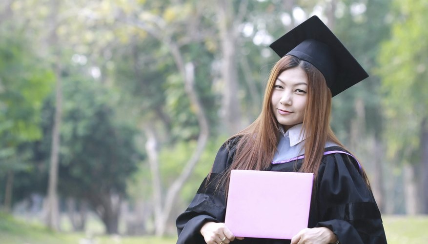 A woman is standing with her diploma while wearing her cap and gown.