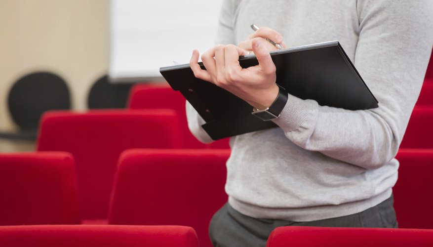 A man filling out a survey in an auditorium.