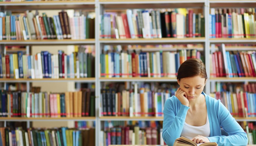 Student reading text book in library