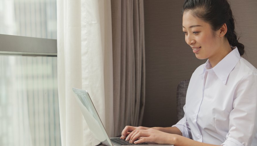 Young woman writing essay on laptop