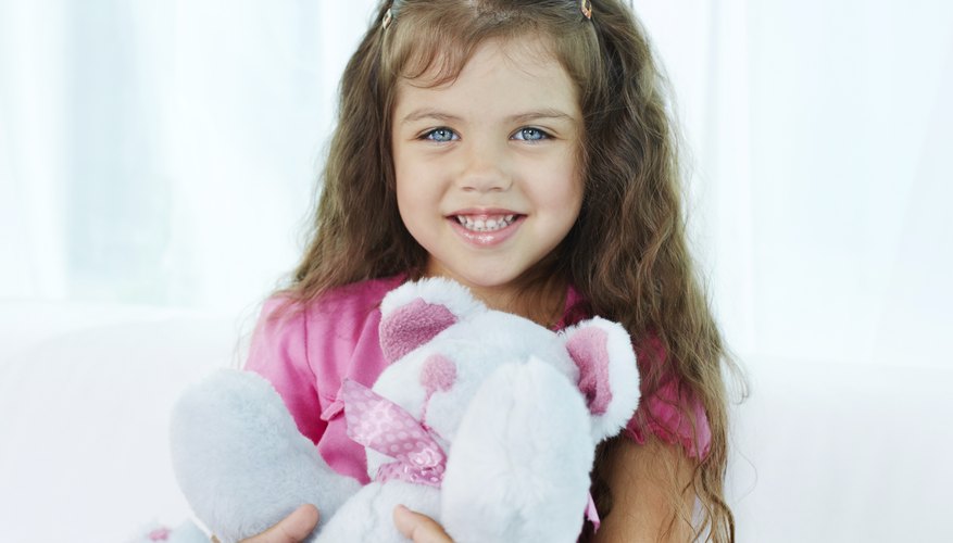 A young girl is presenting her stuffed animal.