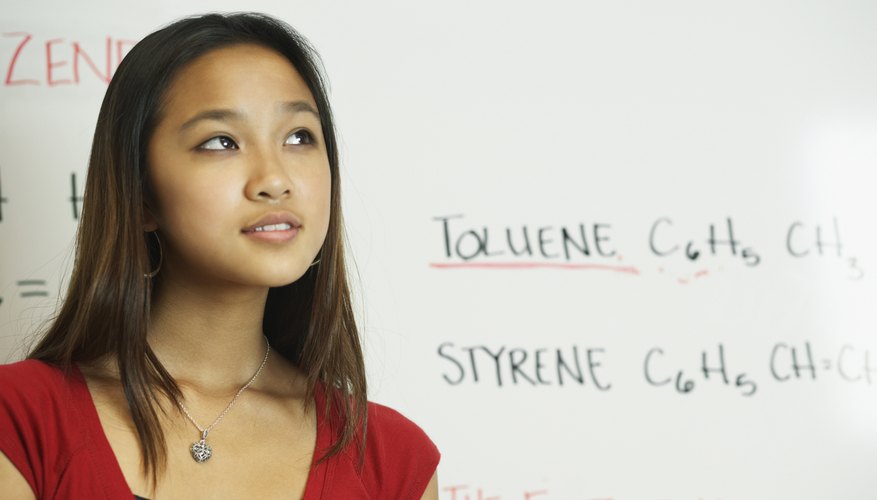 Student thinking in front of whiteboard in classroom.