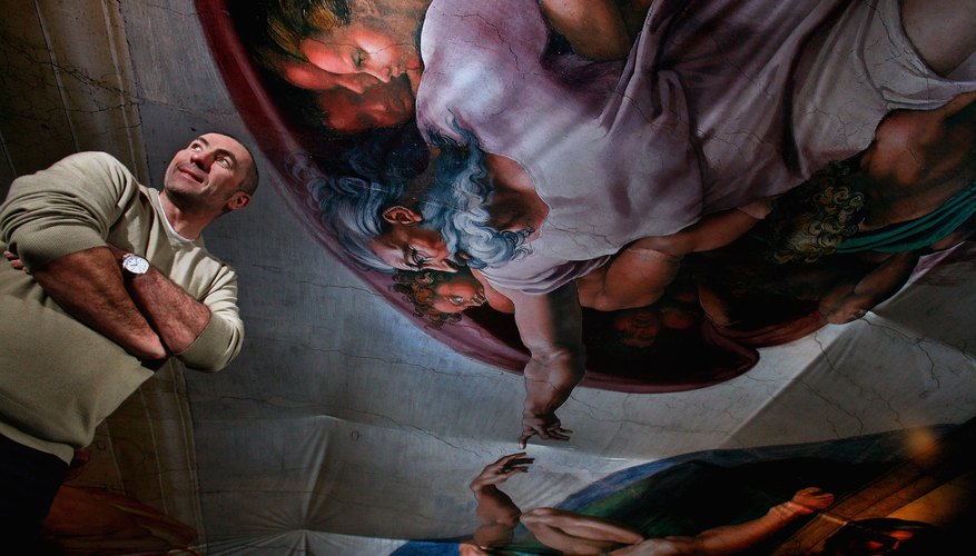 A man standing beneath the painted ceiling in the Sistine Chapel.
