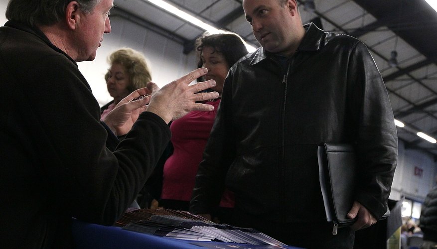 A soldier talks with a military recruiter at a table.