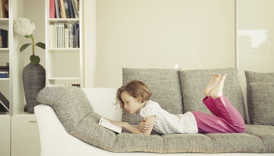 Child reading book on couch.