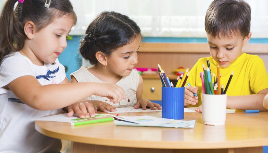 Kindergarten students drawing on paper