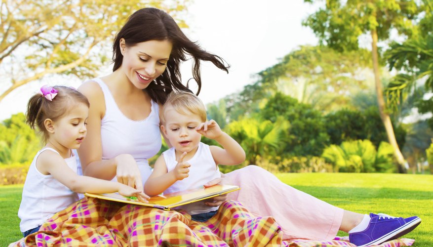 Mother reading outdoors with her two children