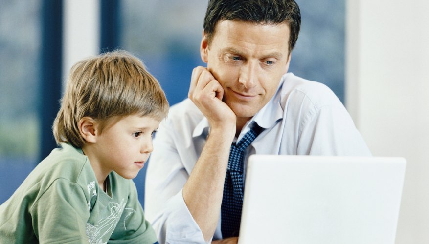 Son looking at laptop in office with father.