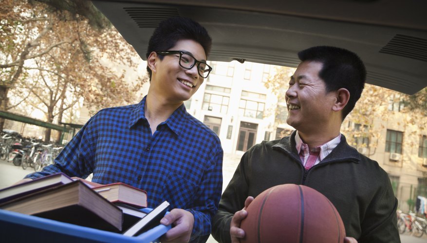 Father helping his son move into college with basketball in hand.