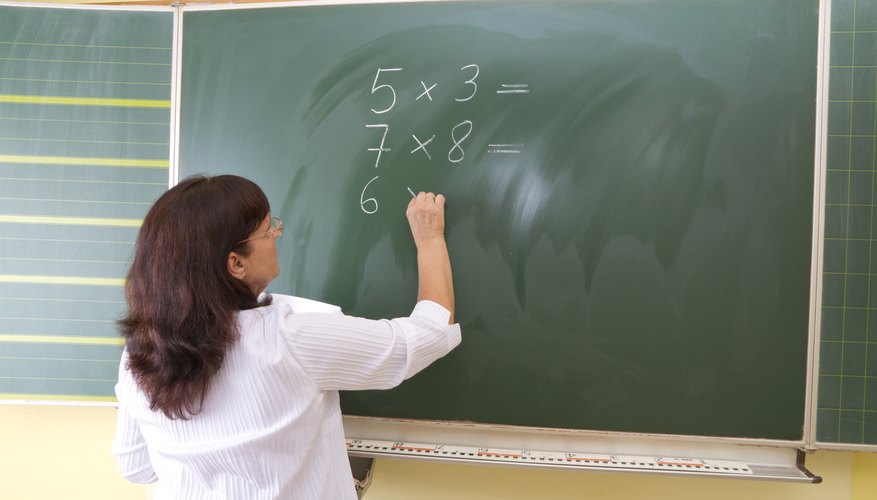 A teacher begins writing out a lunchtime trivia quiz for students.