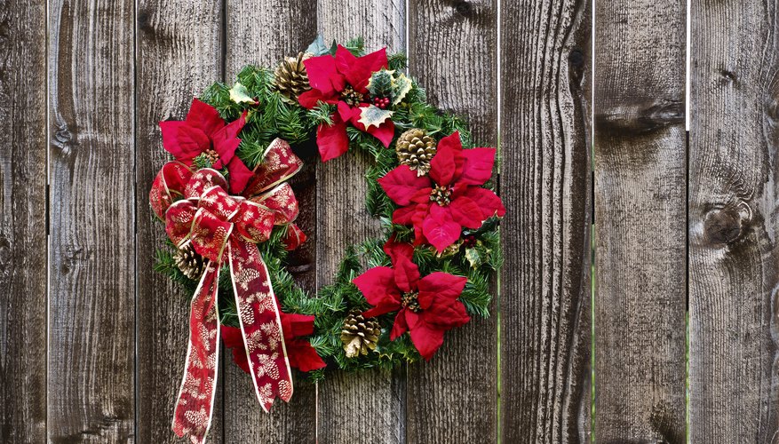 Poinsettia and garland Christmas wreath on a wood surface.