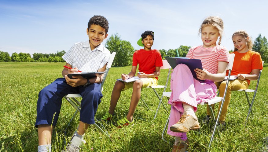 A school nature club sitting outside drawing.