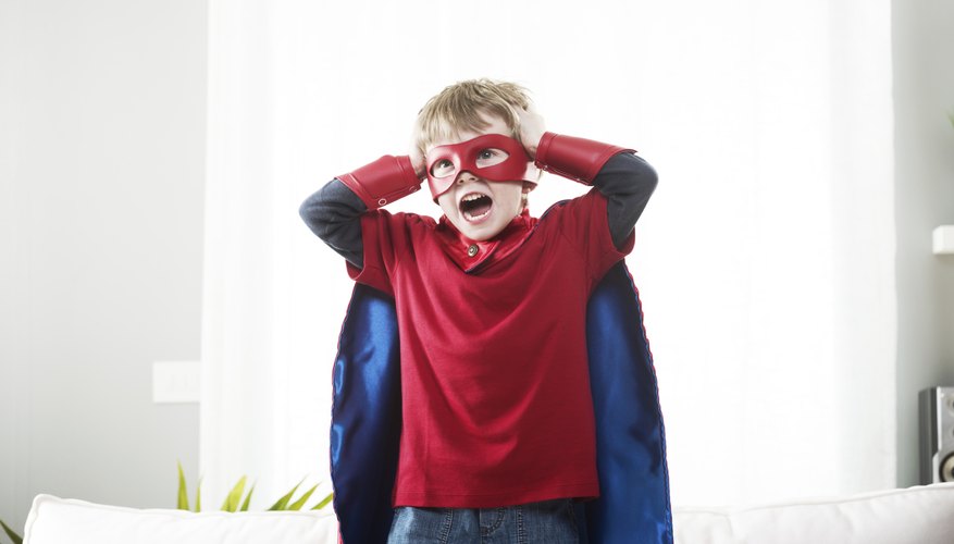 Child dressed up as a superhero with cape and mask