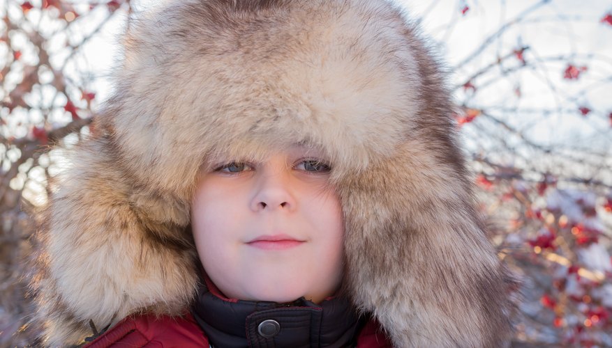 A portrait of a boy in a thick fur hat.