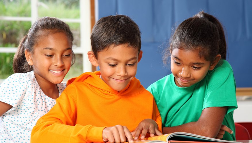A small group of three children sit and read together