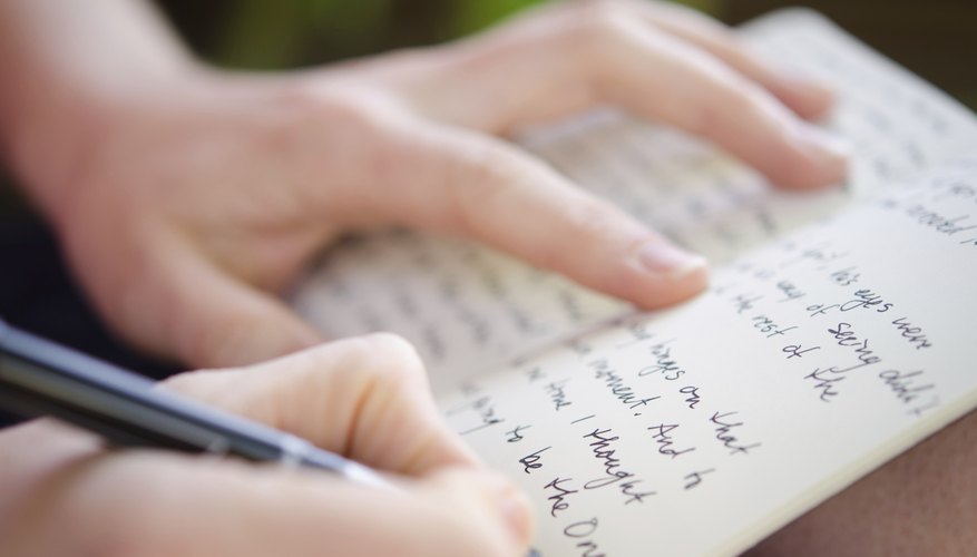 A close up of a young adult in the midst of writing an entry in her journal