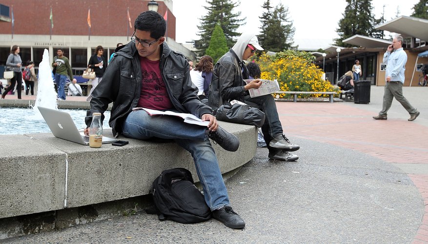 A college student working on a class assignment outside on campus.