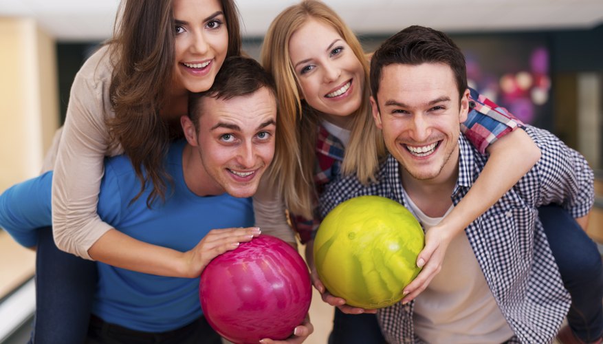 Friends at bowling alley with bowling balls.