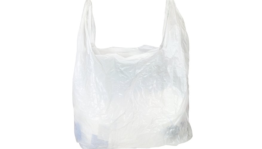 Concept of stop plastic pollution, global warming, recycling plastic,  plastic free, zero plastic. Hand wrapped in a plastic bag. Yellow background  with a black and white subject - a Royalty Free Stock