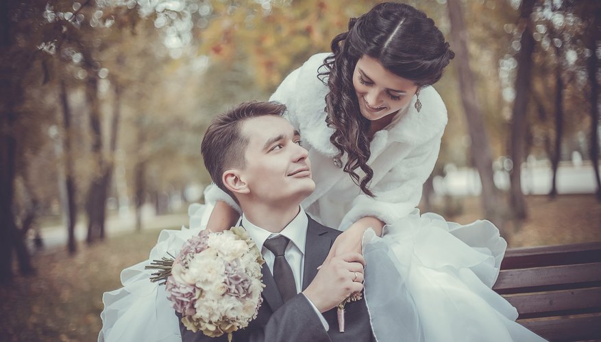 Bride and groom on a park bench in autumn.