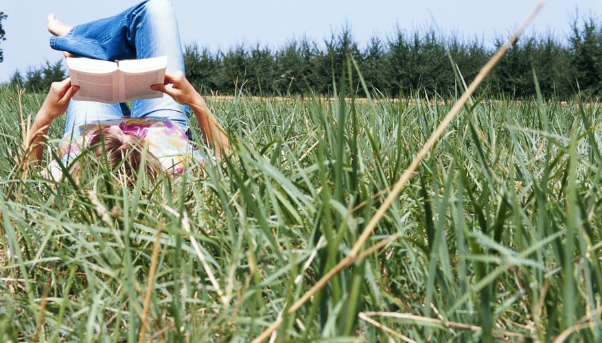 Woman reading book in grass field