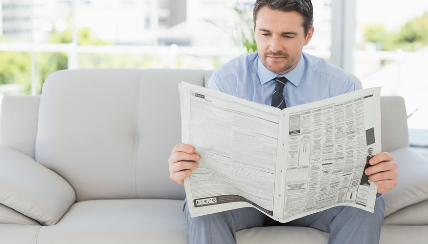Man reading newspaper on couch