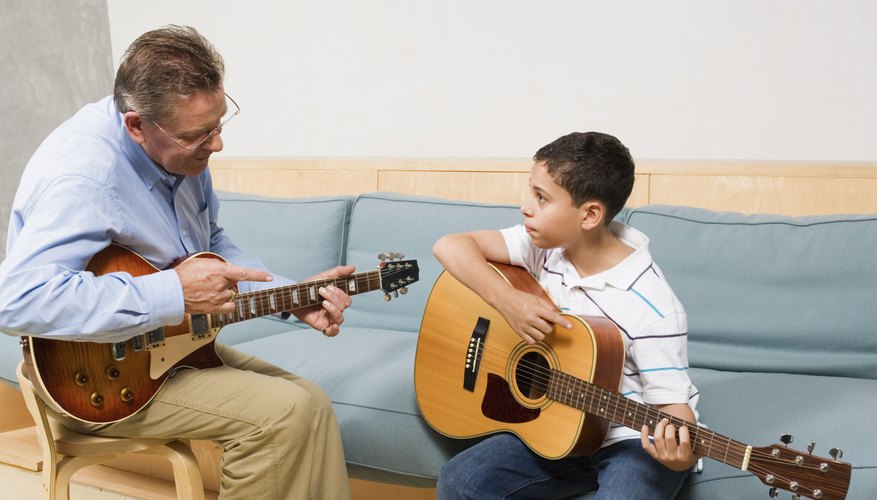 Instructor teaching young boy to play the guitar.