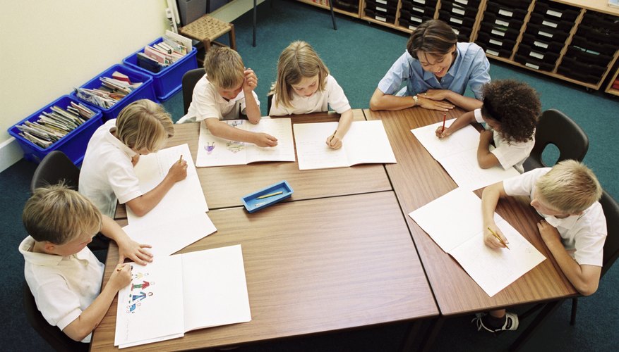A teacher working with students at a group table in a classroom.
